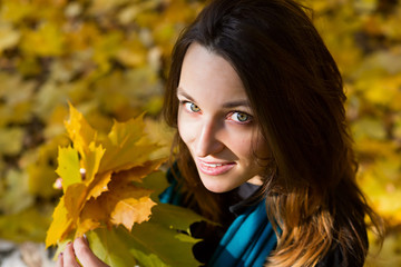 Beautiful happy woman holding autumn leaves in forest