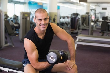 Fototapeta na wymiar Portrait of man exercising with dumbbell in gym