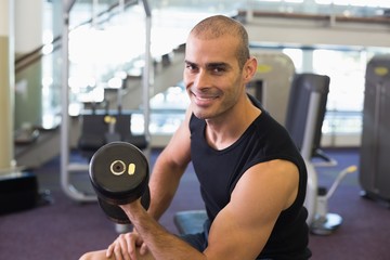 Fototapeta na wymiar Portrait of man exercising with dumbbell in gym