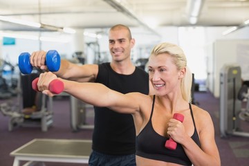 Fototapeta na wymiar Couple exercising with dumbbells in gym