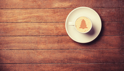 Cappuccino with christmas tree shape on a wooden table.