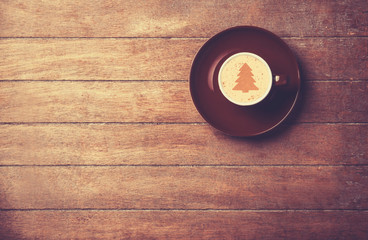 Cappuccino with christmas tree shape on a wooden table.