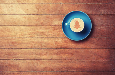 Cappuccino with christmas tree shape on a wooden table.