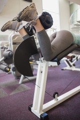 Fototapeta na wymiar Fit woman using weights machine for legs