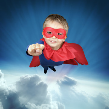 Superhero child flying above the clouds