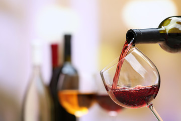Red wine pouring into wine glass, close-up - obrazy, fototapety, plakaty