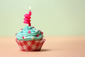 Delicious birthday cupcake on table on light background