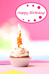 Delicious birthday cupcake on table on bright background