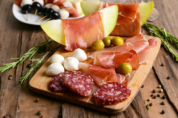 Delicious melon with prosciutto on table close-up