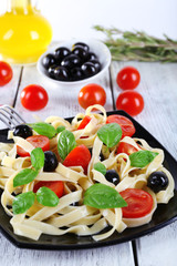 Spaghetti with tomatoes, olives and basil leaves