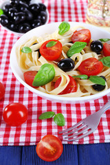 Spaghetti with tomatoes, olives and basil leaves