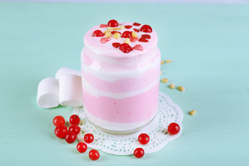 Cranberry milk dessert in glass jar, on color wooden background