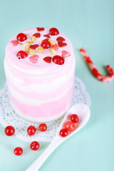 Cranberry milk dessert in glass jar, on color wooden background
