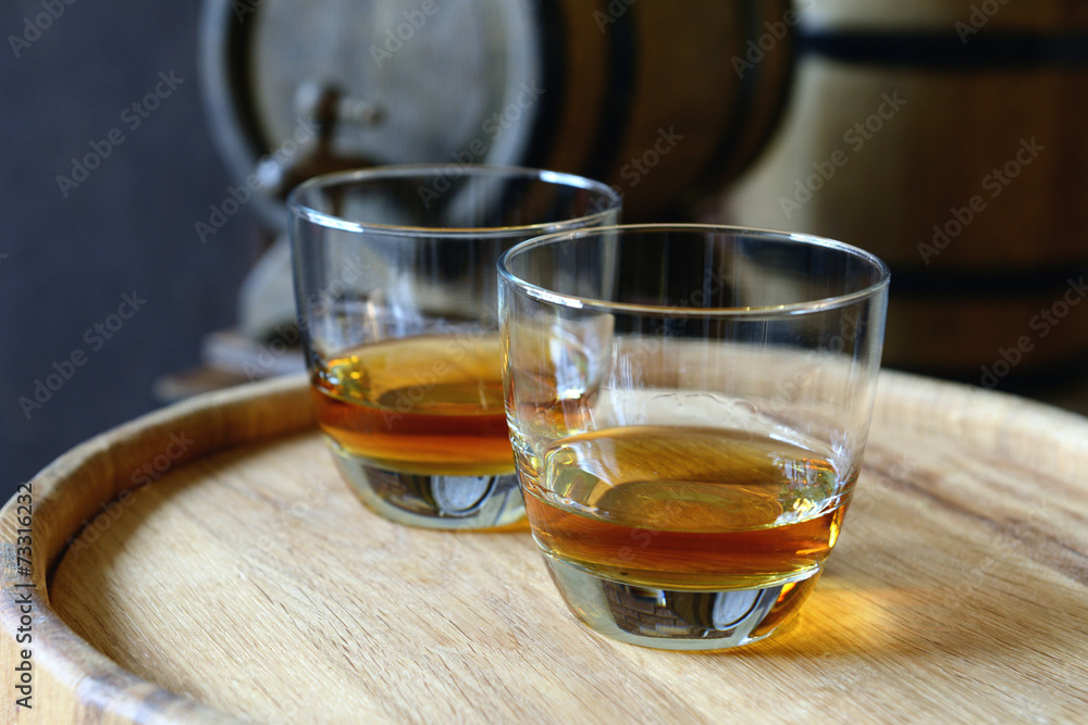 Poster glasses of brandy in cellar with old barrels