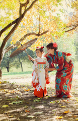 Plakaty  Matka i mała córka w kimonie spacerują po jesiennym parku