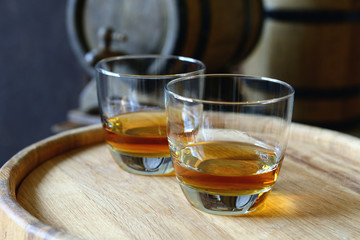 Glasses of brandy in cellar with old barrels