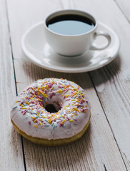 Chocolate top donut and black coffee on a table top