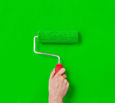 Hand With Paint Roller On Green Wall