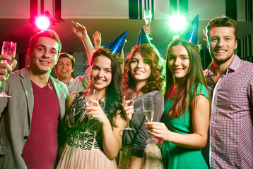 smiling friends with glasses of champagne in club