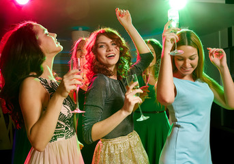 smiling friends with glasses of champagne in club