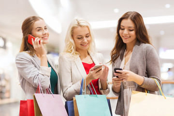 happy women with smartphones and shopping bags