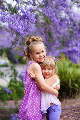 Two little sister love and have a fun in beautiful blossom garde