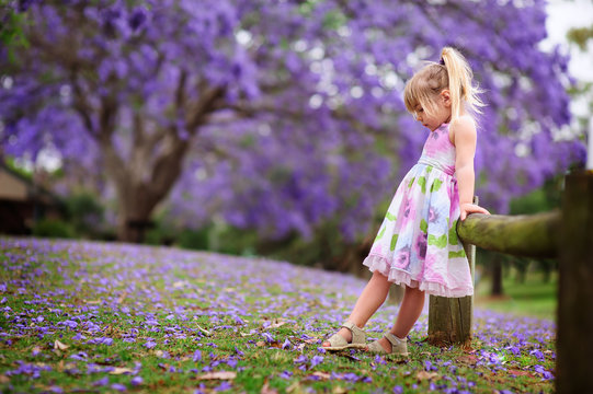 happy little girl has a fun in blossom jacaranda garden