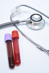 Blood test tube and stethoscope on white background.