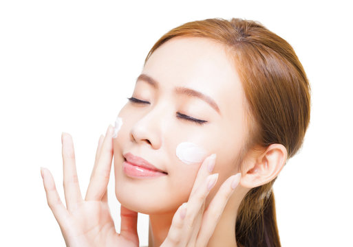 beautiful young woman applying cosmetic cream  on her face