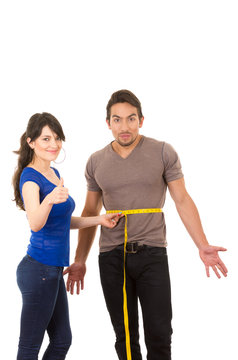 beautiful girl holding measuing tape around handsome muscular