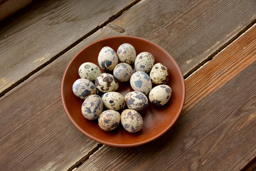 Fresh quail eggs in a ceramic plate on a wooden background
