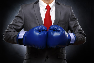 Business man in blue gloves on dark background