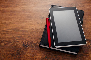 Pen and Tablet on Top of Closed Book at the Table