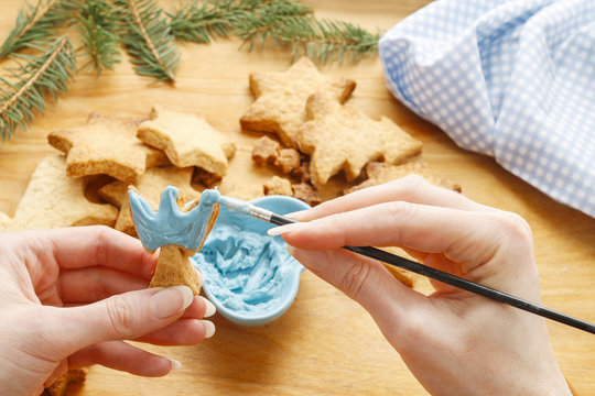 Decorating gingerbread cookies with blue and white icing.