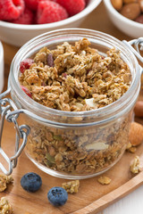 glass jar with homemade granola and fresh berries, vertical