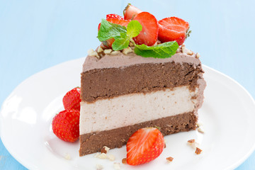 piece of chocolate cake of three layers with fresh strawberries
