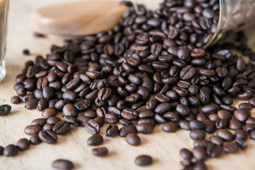 Closeup of roasted coffee beans on the wooden table, preparing materials for brewing fresh coffee.
