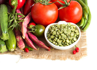 Green peas in and vegetables on a white background