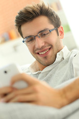 Casual guy using smartphone, relaxing in couch