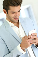 Man with blue jacket sending short message on smartphone