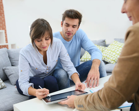 Young couple signing financial contrat on digital tablet