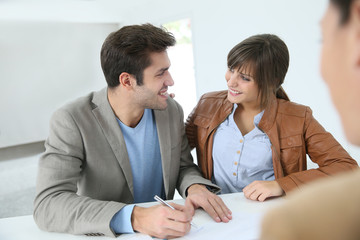 Young couple in real estate agency signing property agreement