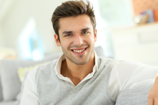 Portrait of smiling casual guy sitting in sofa