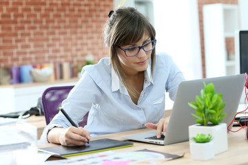 Creative young woman working in office with graphic tablet