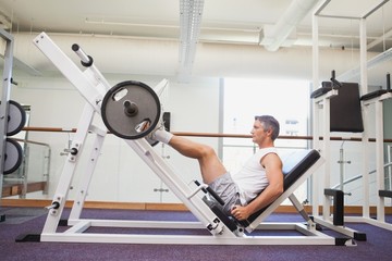 Fit man lifting heavy barbell with legs