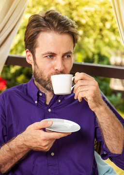 Man drinking morning coffee outdoor on garden terrace