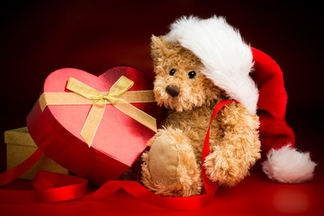 Teddy Bear Wearing a Christmas Hat and Hugging a Box