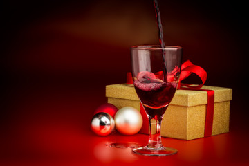 Red Wine Poured Into Glass in Front of Golden Present