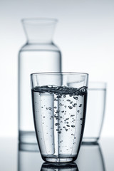 glass with water and a carafe in the background