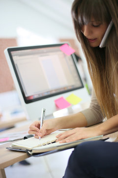 Young woman at work writing appointment in agenda